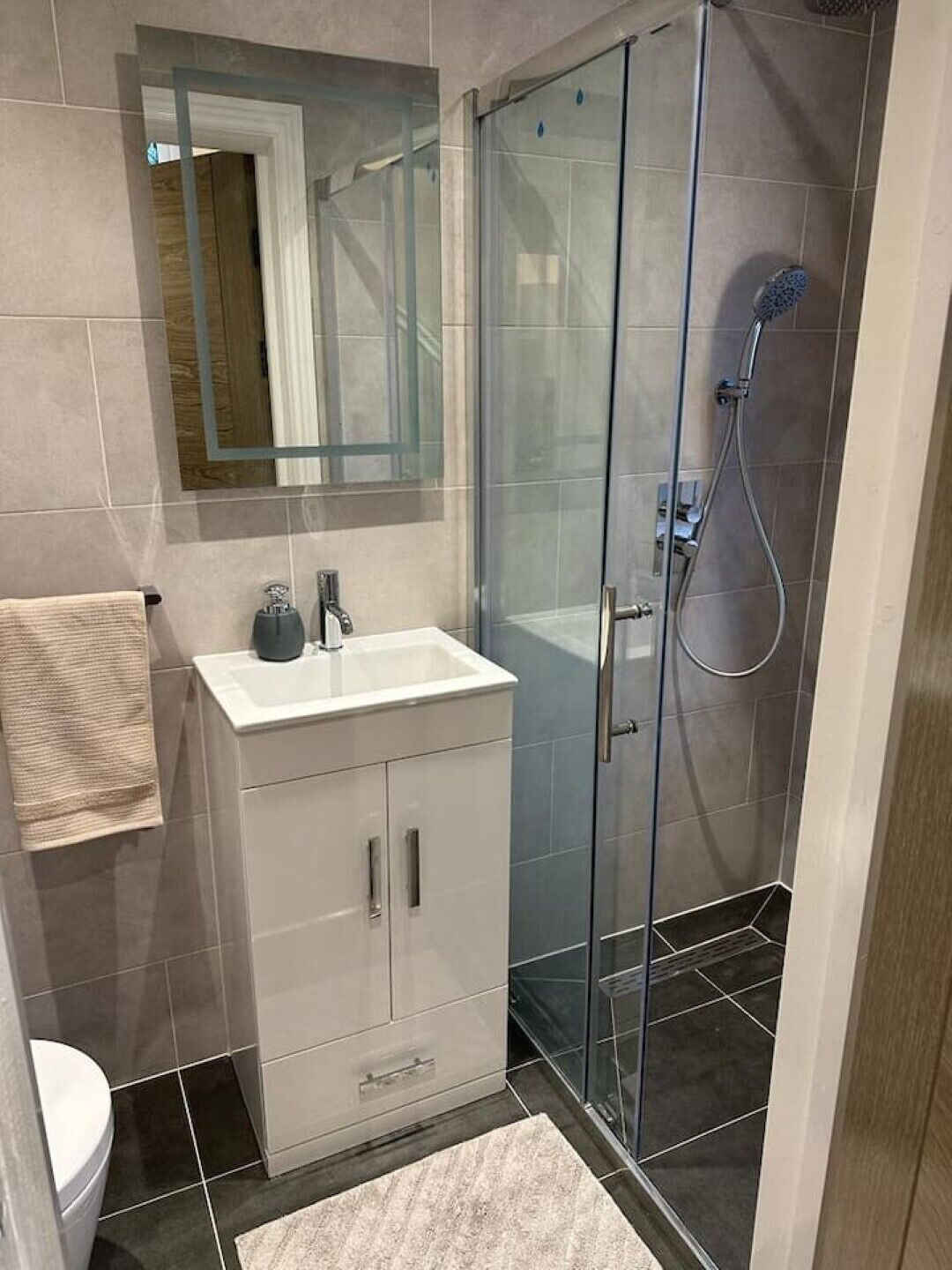 Une salle de bain moderne avec une douche à parois de verre, un lavabo blanc et un miroir au-dessus.