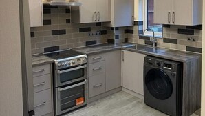 A modern kitchen with a skylight, stainless steel appliances, and a built-in washing machine. - The Grey Retreat (Shepperton)