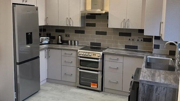 A modern kitchen with a skylight, stainless steel appliances, and grey cabinetry. - The Grey Retreat (Shepperton)