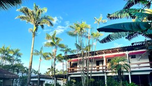 A two-story building with a balcony, surrounded by palm trees and a grassy area. - Hotel Casa Paradiso (Guarujá)