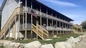 A two-story building with a wooden exterior, a balcony on the second floor, and a staircase leading to the entrance. - Deluxe Ocean View Room (Brooklin)