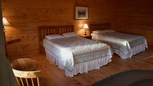 Ein rustikales Zimmer mit zwei Holzbetten, einem kleinen Tisch und einem Stuhl.