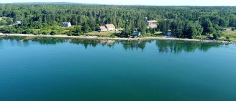 A lakeside property with multiple houses, a dock, and dense forest in the background.