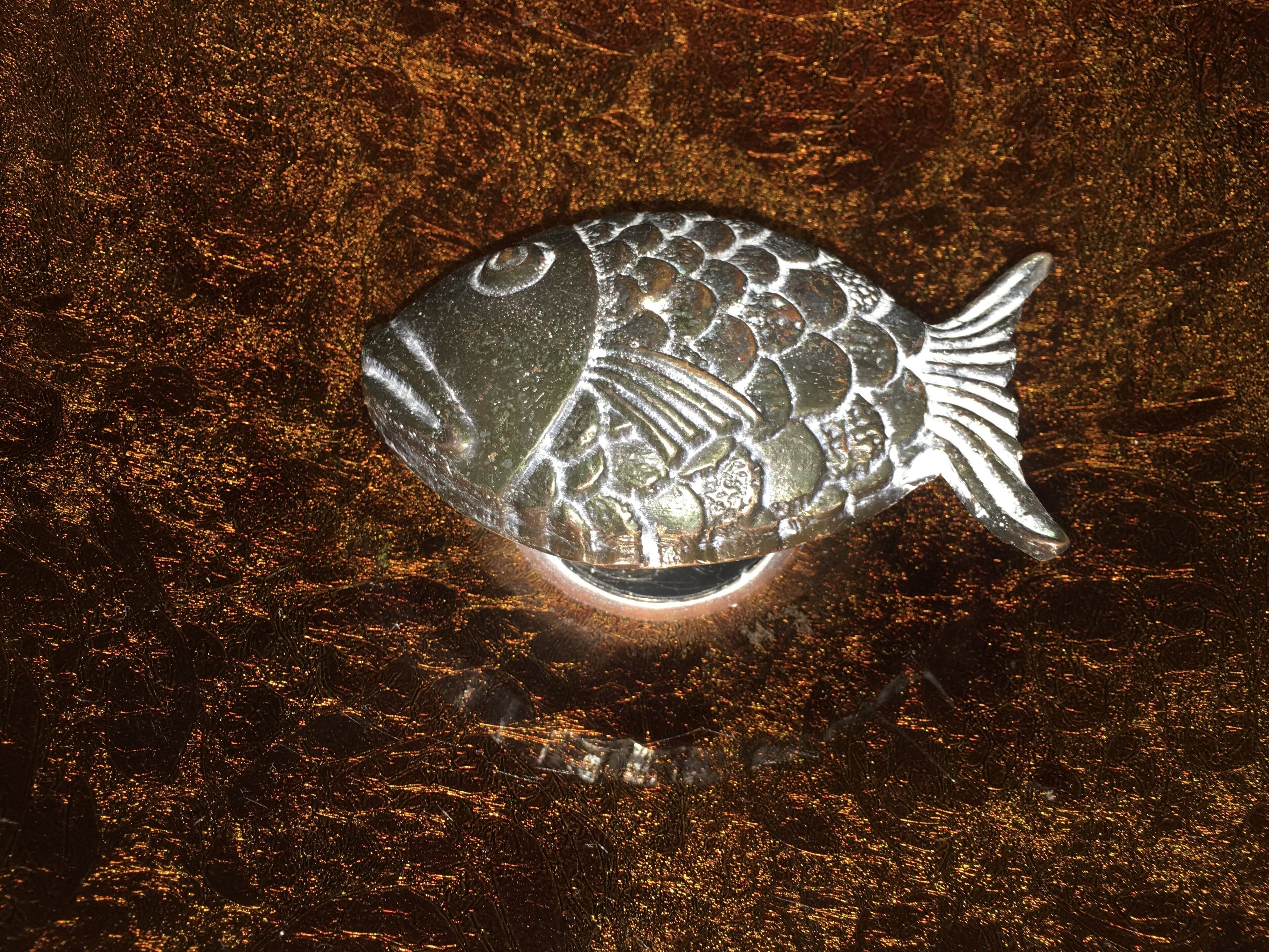 A fish-shaped sculpture on a textured surface.