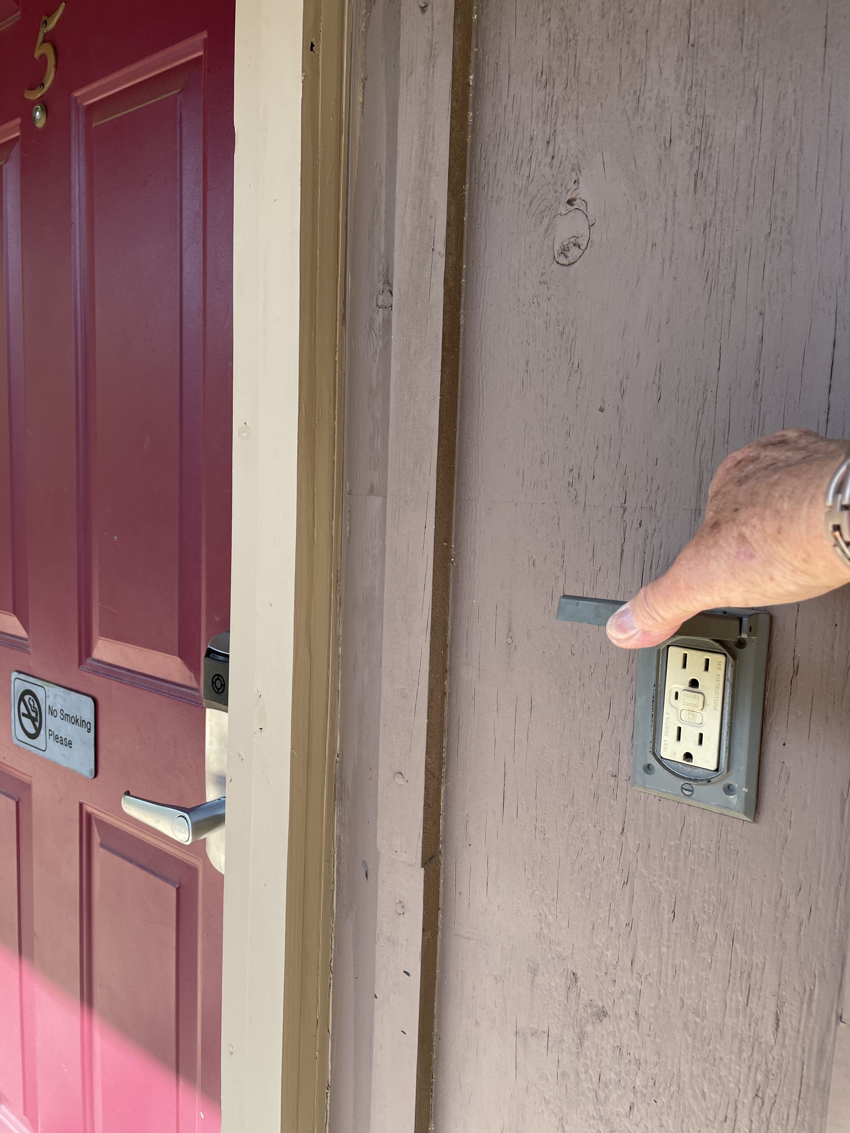 A door with a 'No Smoking' sign, a doorbell, and an electrical outlet.