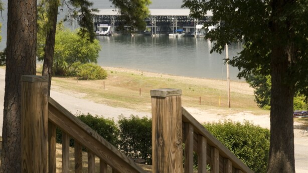 A wooden deck with a railing overlooking a body of water and a bridge in the distance. - Mountain Harbor Queen Guest Room on Lake Ouachita by RedAwning (Mount Ida)