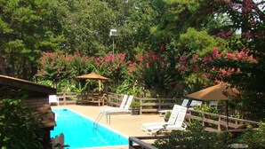 A backyard with a swimming pool, lounge chairs, and a wooden fence. - Mountain Harbor Queen Guest Room on Lake Ouachita by RedAwning (Mount Ida)