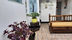 A cozy room with a wooden bench, a potted plant, and a wall decorated with artwork and a 'SALIDA' sign. - Hotel Posada Santa Elena (Tunja)