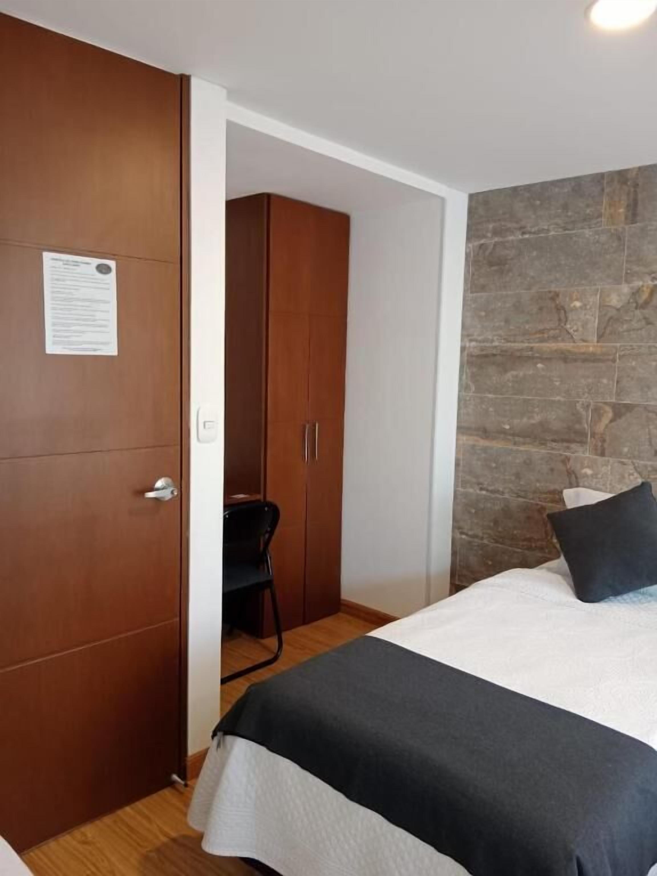 Quarto com cama, guarda-roupa e parede de pedra.
