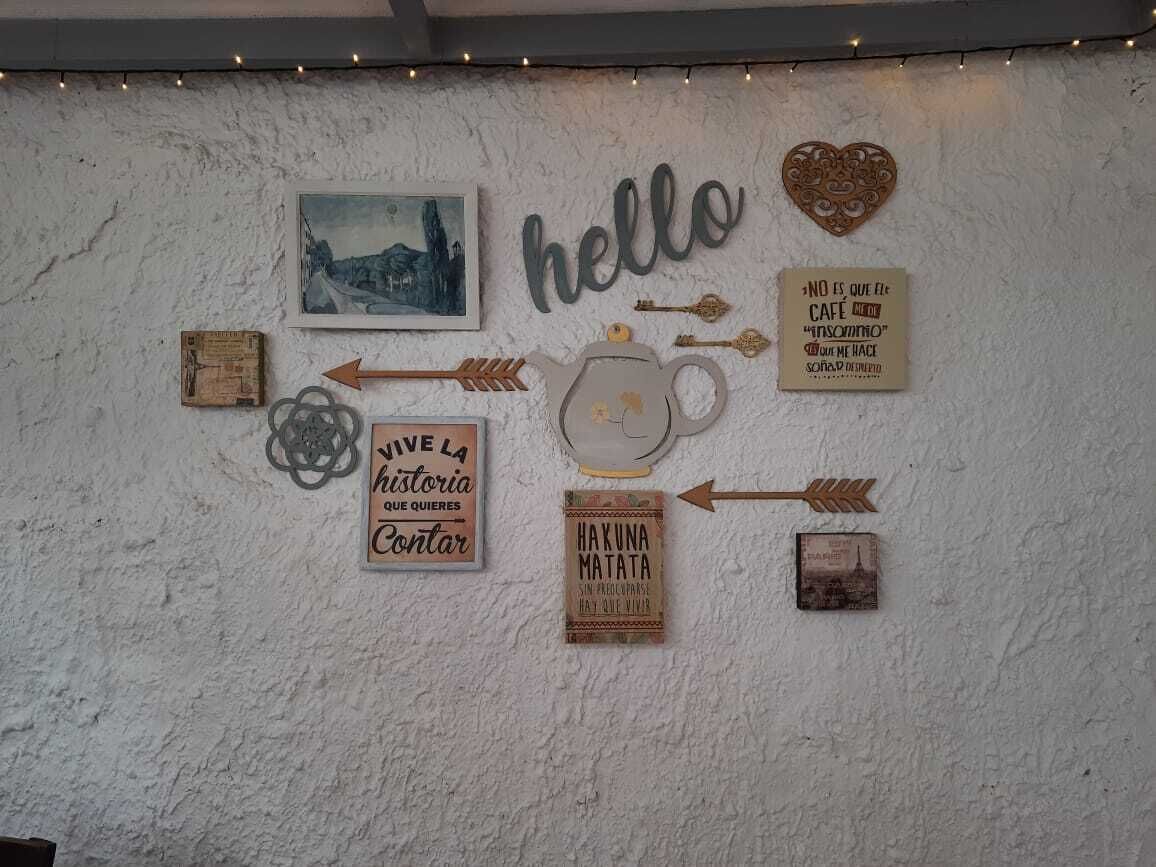 A wall with various decorative items including a 'hello' sign, a heart, a teapot, and several framed sayings.