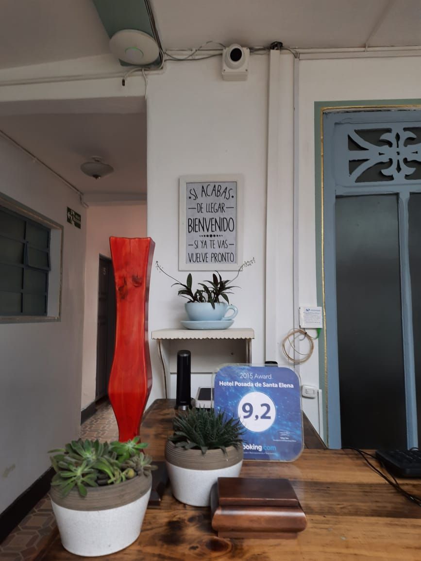 A reception area with a welcome sign, potted plants, a red vase, and a blue award plaque.