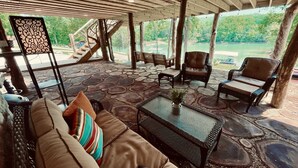 An outdoor seating area with stone flooring, wicker furniture, and a view of a lake. - “Twin Timbers” 11 bdrm,sleeps 38! hotubs, docks, 3 firepits, sxs, optional boats (Lafollette)