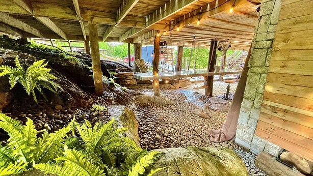 An indoor garden with wooden beams, a stone wall, and ferns. - “Twin Timbers” 11 bdrm,sleeps 38! hotubs, docks, 3 firepits, sxs, optional boats (Lafollette)