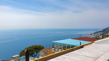 Vista sulla costa da un punto elevato, con mare cristallino e una linea di costa distante con edifici.