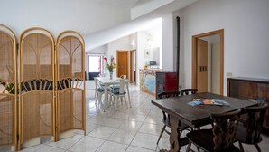 Uma sala espaçosa com mesa de jantar, cadeiras, cozinha e um painel decorativo.