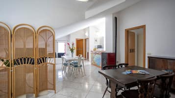 Un'ampia zona giorno con tavolo da pranzo, sedie, angolo cottura e un pannello decorativo.