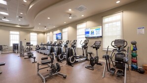 Un gimnasio con equipos de ejercicio variados, incluyendo cintas de correr, elípticas y estaciones de pesas.
