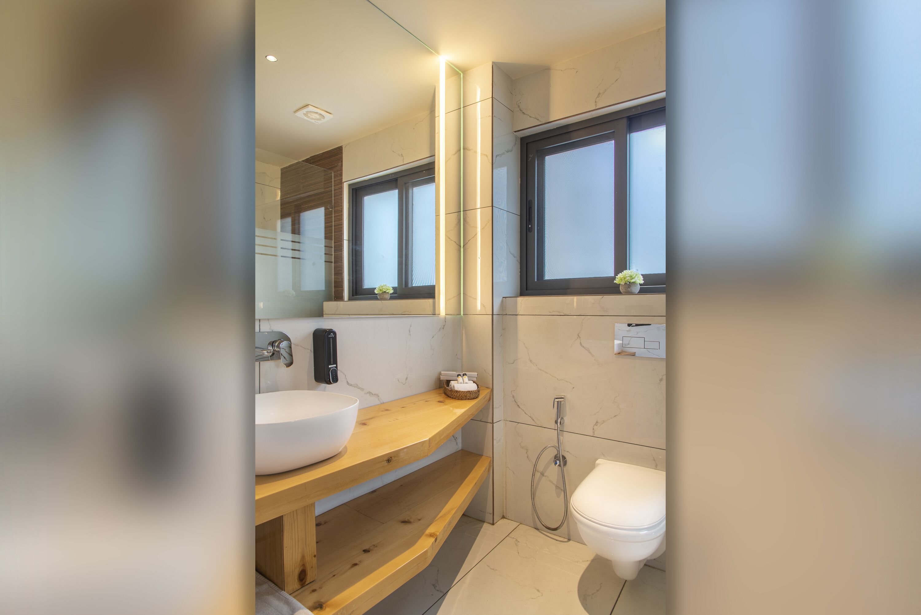 A modern bathroom with a wooden vanity, a white sink, a mirror, and a toilet.