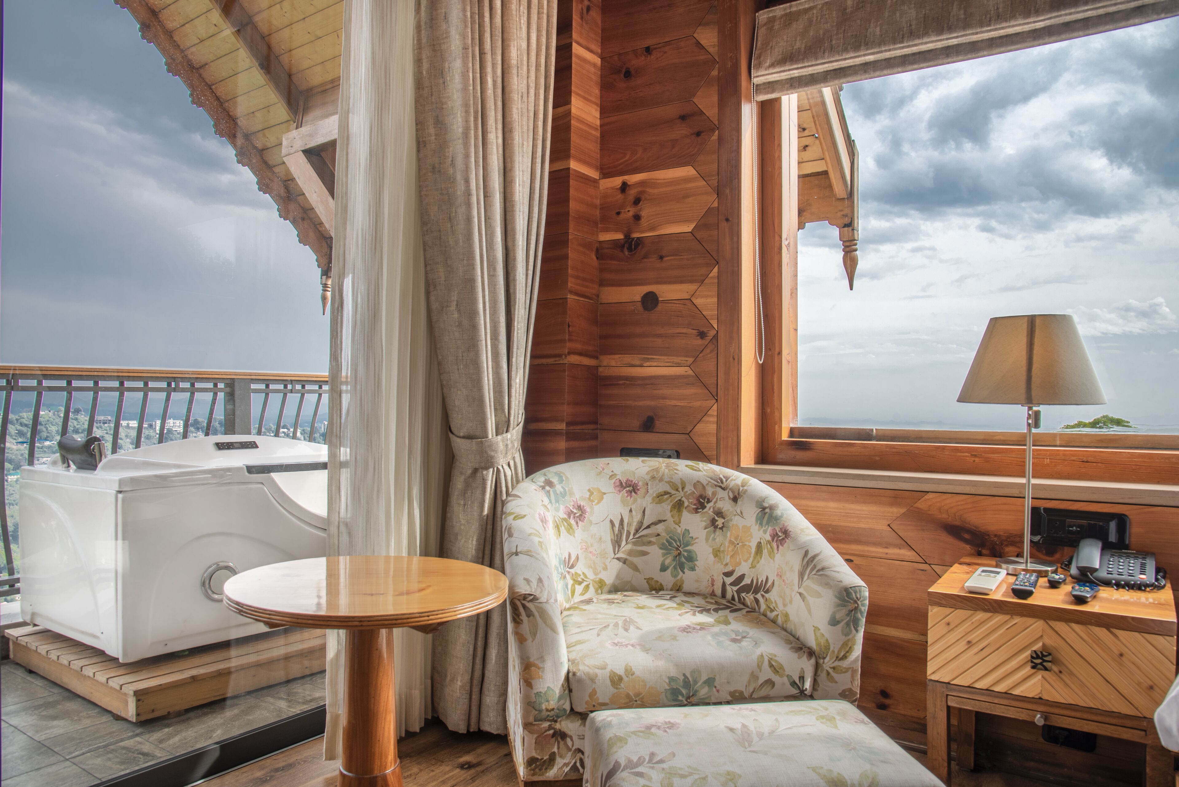 A wooden cabin room with a sofa, a small table, a lamp, and a view of the sky.