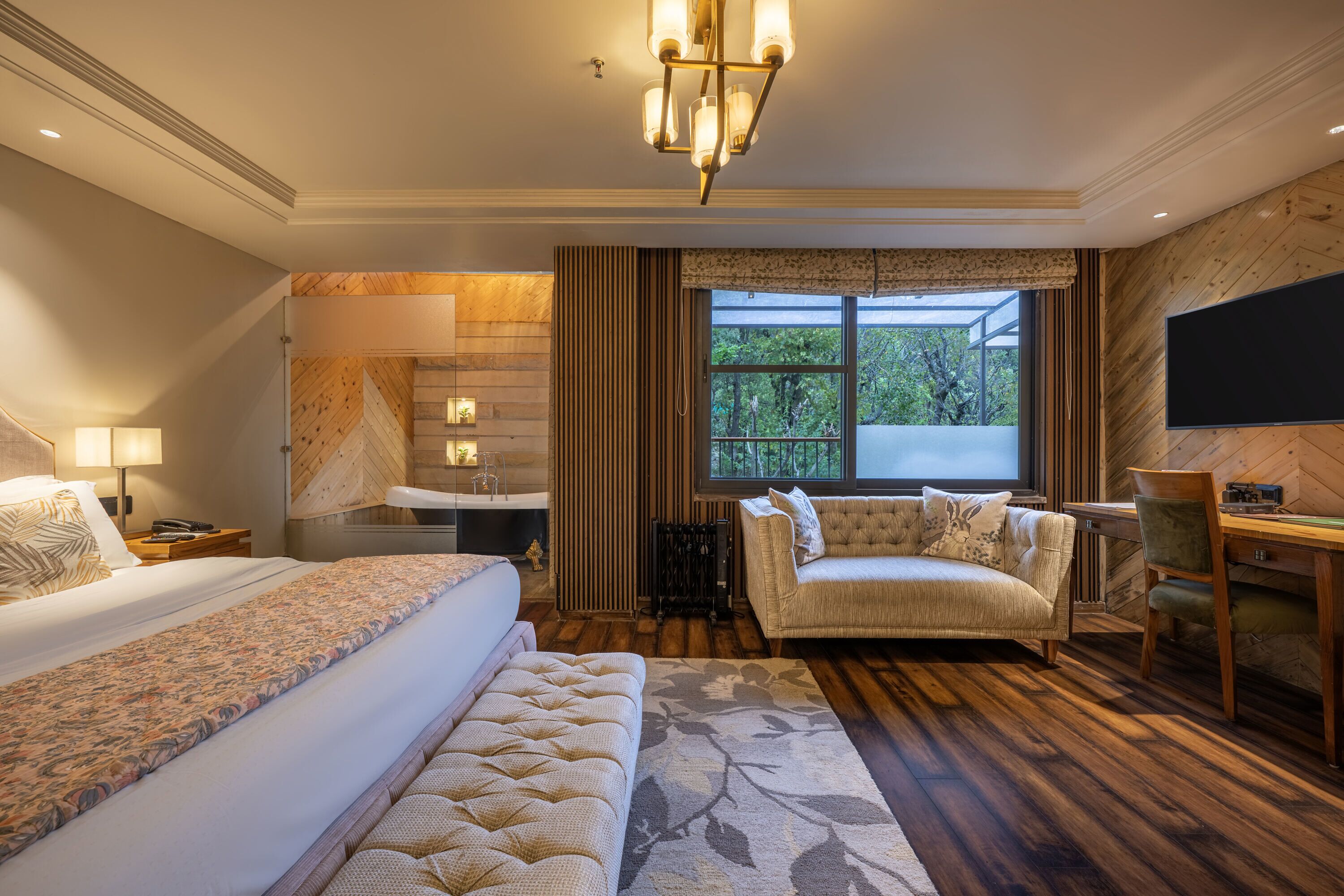Habitación de hotel con cama, sofá, escritorio, televisión, ventana y baño.