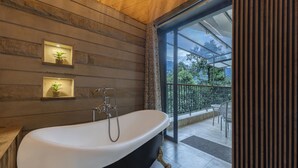 Un baño moderno con una bañera independiente, paredes de madera y una puerta de cristal que da a un área exterior.