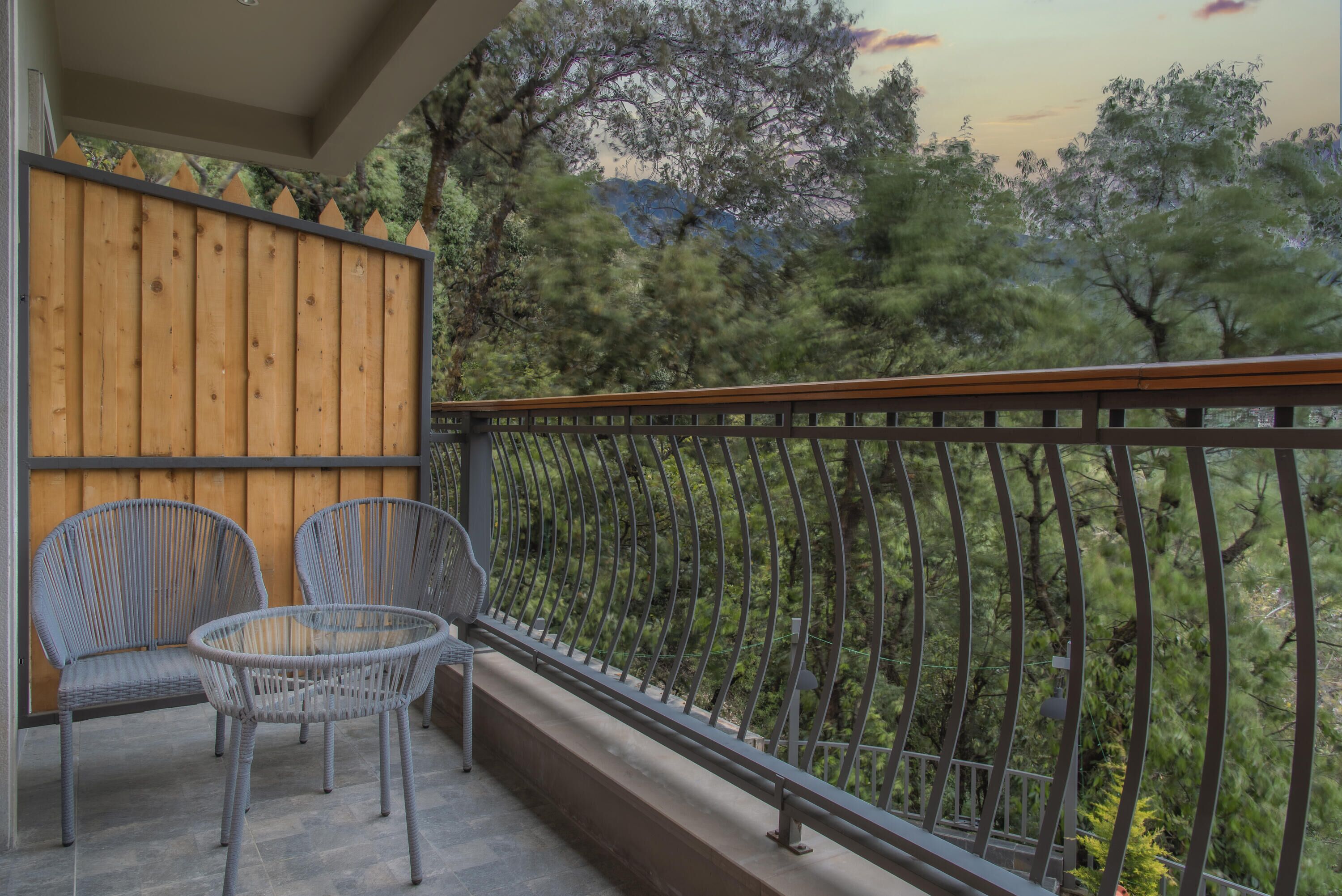 A balcony with two wicker chairs and a wooden fence.