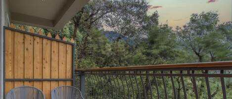 A balcony with two wicker chairs and a wooden fence.