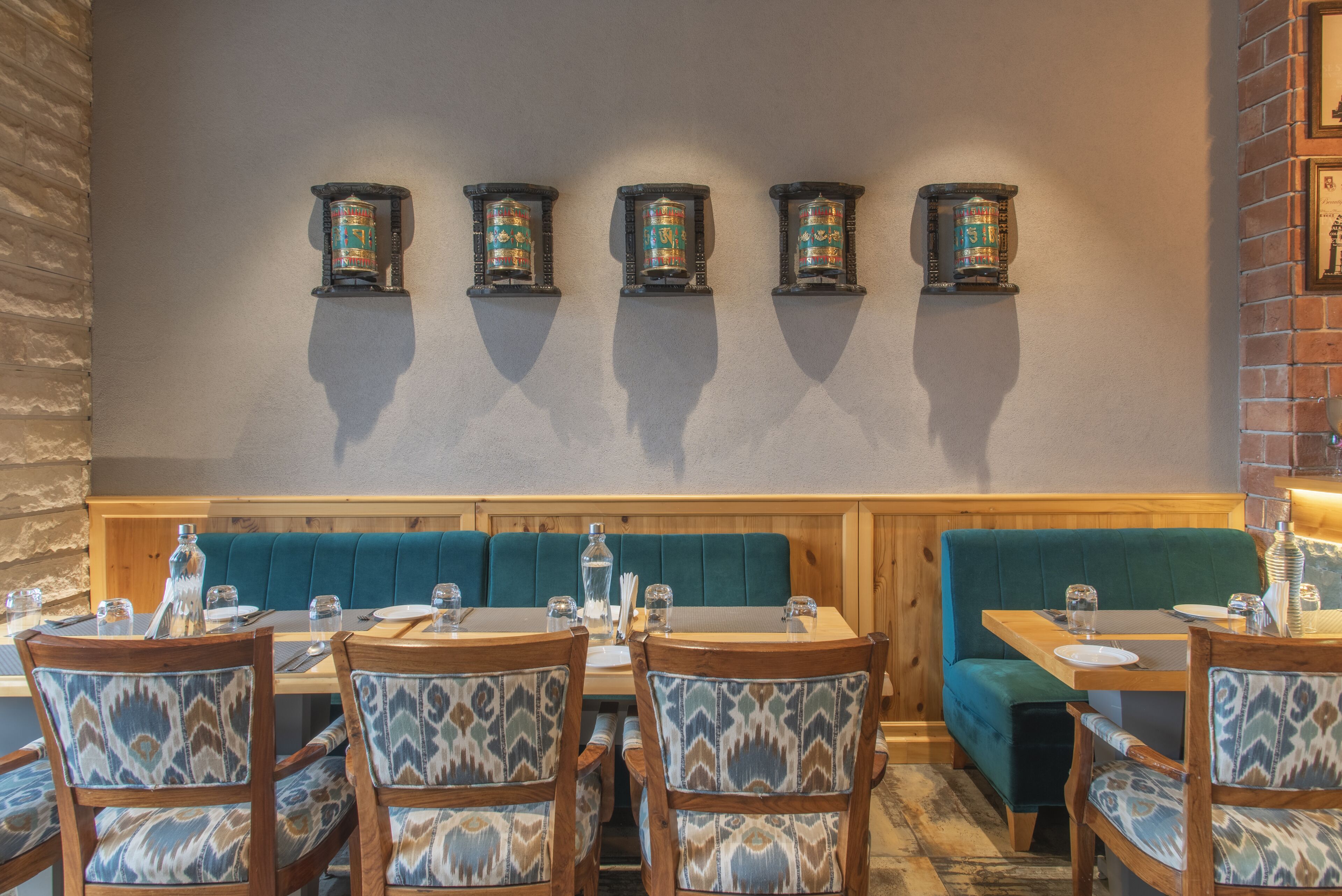 A restaurant interior with wooden tables and chairs, teal cushioned booths, and wall-mounted decorative canisters.