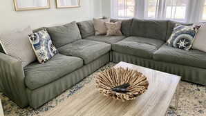 A modern living room with a sectional sofa, a coffee table with a unique wooden centerpiece, and framed artwork on the wall.