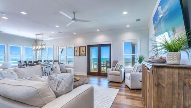 A spacious living room with a large sofa, a coffee table, and a wooden cabinet. There is a large window providing a view of the ocean. - Stella Maris- GULF FRONT 7BR/7BA House with private heated POOL, Views from every room (Mexico Beach)