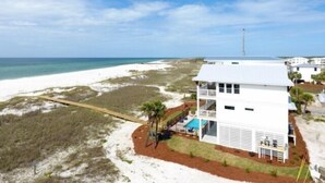 A white two-story beachfront house with a balcony, a small pool, and a view of the beach and ocean. - Stella Maris- GULF FRONT 7BR/7BA House with private heated POOL, Views from every room (Mexico Beach)