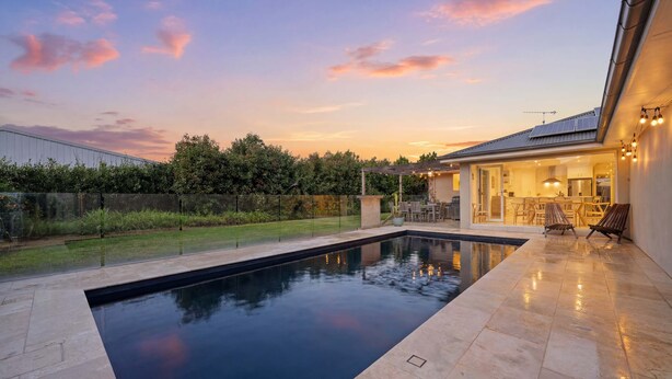 Une piscine avec un espace patio, un coin salon extérieur couvert et une vue sur le ciel.