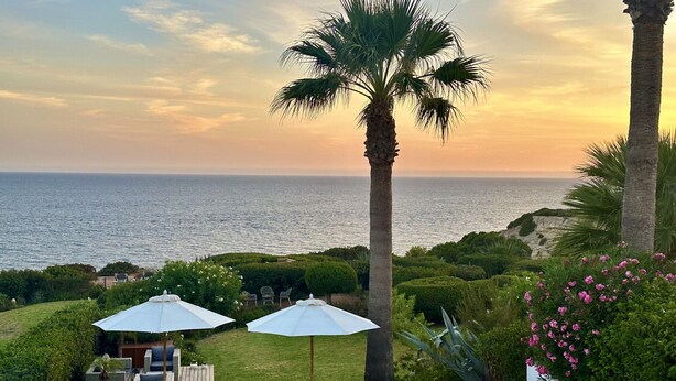 A patio with outdoor furniture, a table, and two umbrellas overlooking the sea. - Casa Girassol, villa wih private pool at Algarve Clube Atlântico (Carvoeiro)