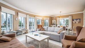 Ein geräumiges Wohnzimmer mit einer großen Couch, einem Couchtisch und einem Essbereich mit Tisch und Stühlen.