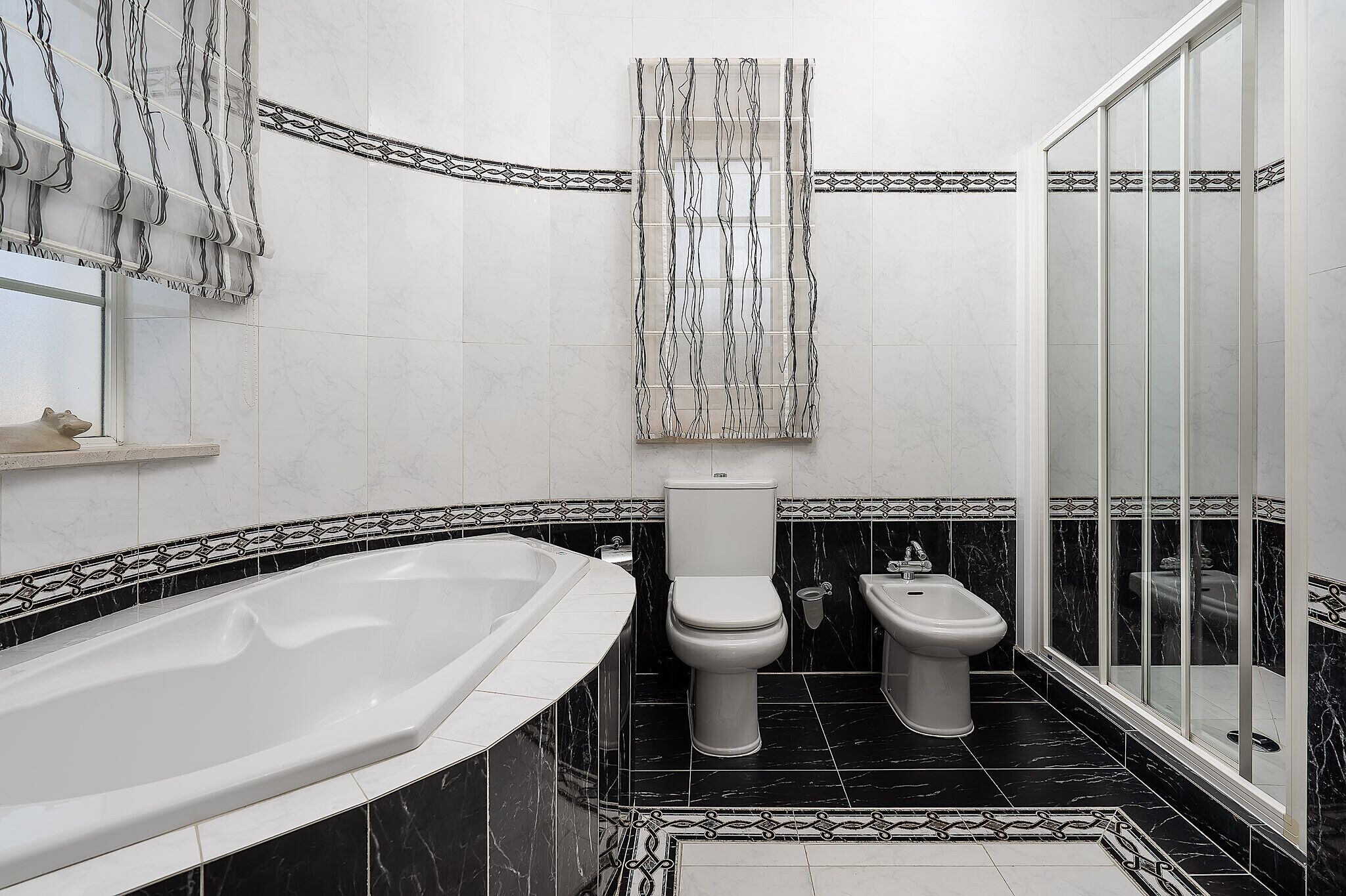 Une salle de bain équipée d’une baignoire, de toilettes, d’un bidet et d’une douche à parois en verre.