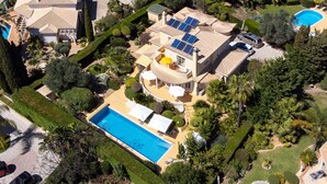 Ein großes Haus mit Swimmingpool, Solaranlage und einem gepflegten Garten.