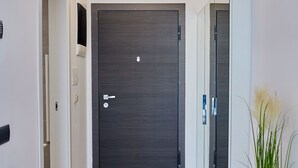 A modern hallway with a dark wooden door, a light wooden floor, and a potted plant. - Grup Casa Del Mar (Năvodari)