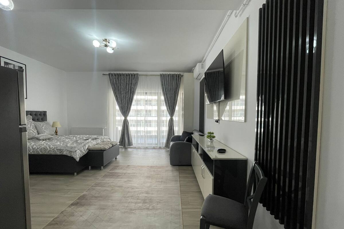 Un dormitorio moderno con cama, escritorio, silla y televisor.