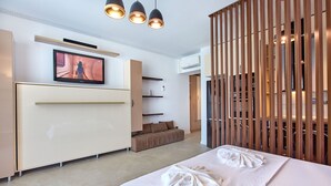 A modern hotel room with a large bed, a TV mounted on the wall, a sofa, and a wooden partition. - Grup Casa Del Mar (Năvodari)