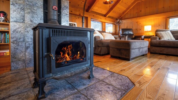 Una sala de estar acogedora con estufa de leña, pisos de madera y una chimenea de piedra.