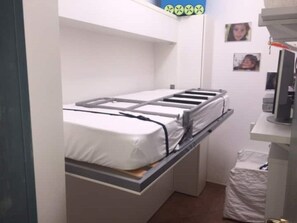 Een stapelbed in een kleine kamer met een bureau en een stoel.