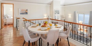 A dining area with a round table set for four, surrounded by white chairs. - Palheiro Village villa, priv pool | Palheiro Ocean (São Gonçalo)