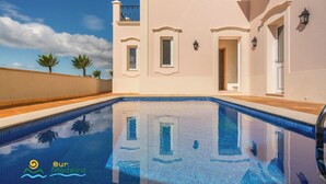 A swimming pool with a clear blue water surface, surrounded by a building with white walls and balconies. - Palheiro Village villa, priv pool | Palheiro Ocean (São Gonçalo)