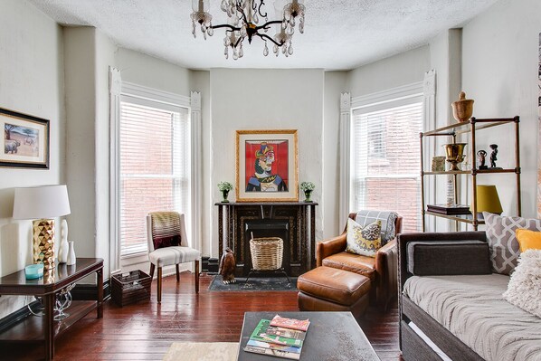 A living room with a fireplace, a chandelier, and a bookshelf. - Comfort, Style, True Hospitality in the Heart of Old Louisville (Louisville)