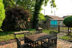 A wooden outdoor patio with a table and chairs, surrounded by a wooden fence and lush greenery. - Comfort, Style, True Hospitality in the Heart of Old Louisville (Louisville)