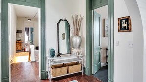 A hallway with a white console table, a mirror, and a vase. There are two wicker baskets on the floor. - Stylish Gem in the Heart of Old Louisville (Louisville)