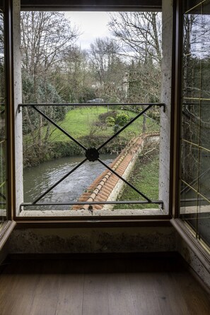 A room with a large window overlooking a river and a bridge. - Moulin du Fontcourt (Chasseneuil-sur-Bonnieure)