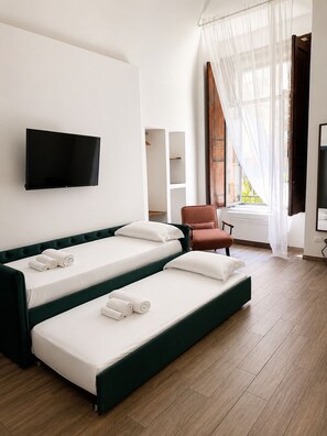 A hotel room with a bed, a television, a chair, and a window with curtains.