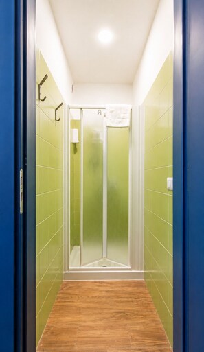 A narrow hallway with green-tiled walls and a wooden floor leading to a glass door. - Palazzo Belmosto (Naples)