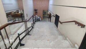 A staircase with marble steps and wooden railings leading to a landing area with a reception desk and a potted plant. - Ap Copacabana 200m da praia - CP5 (Rio de Janeiro)